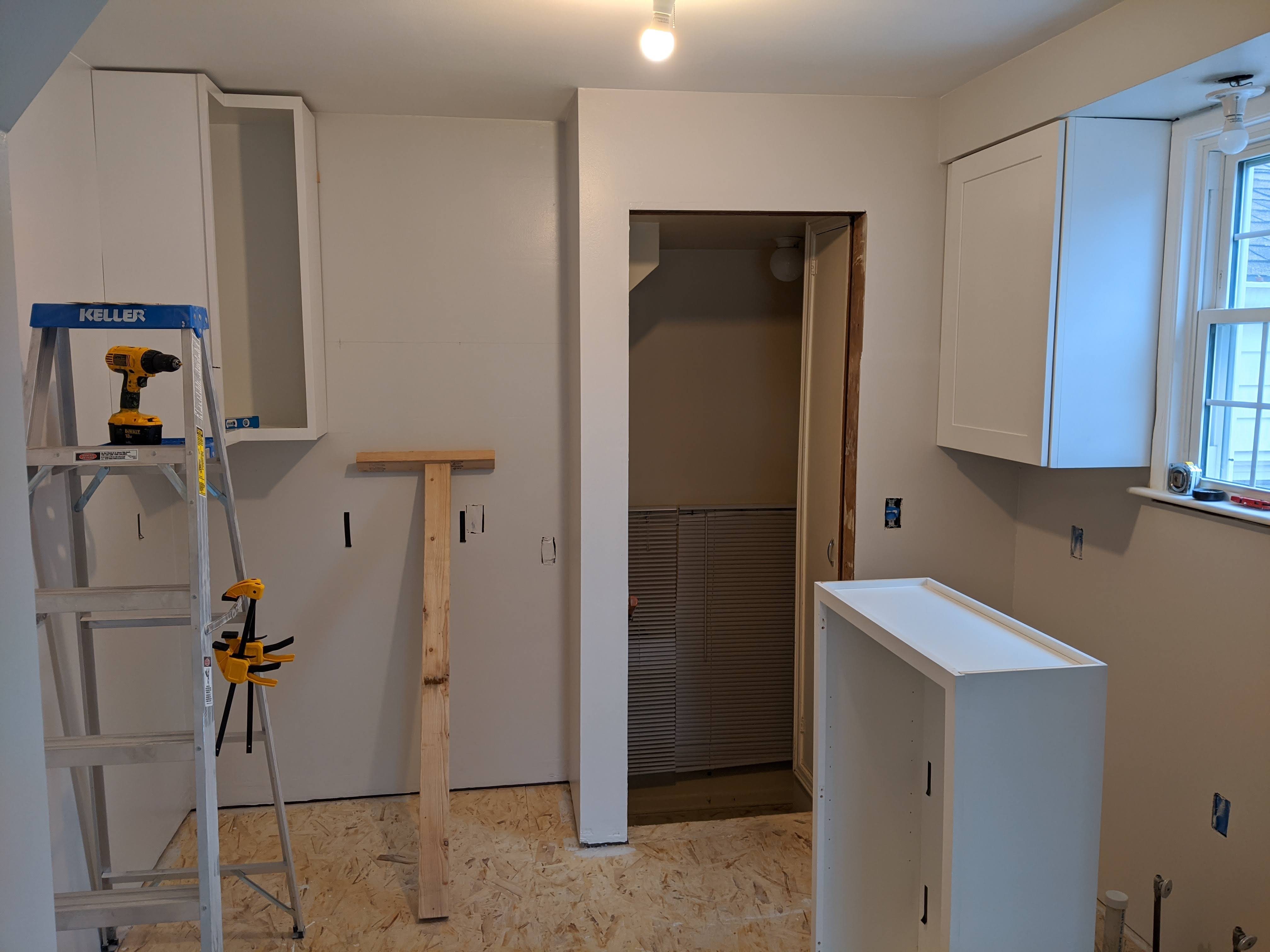 A kitchen in construction, handing top cabinets
